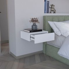 a white nightstand with a book on it next to a bed