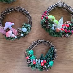 three wreaths with decorations on them sitting on a table