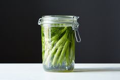 a jar filled with green vegetables sitting on top of a table