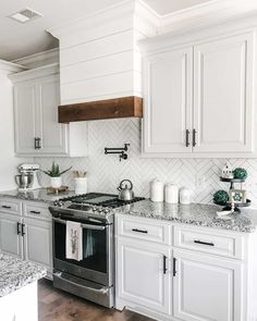 a kitchen with white cabinets and marble counter tops, stainless steel appliances and an oven