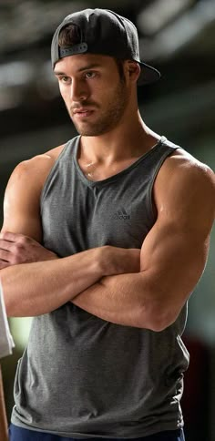 a man with his arms crossed wearing a hat