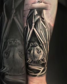 a man's arm with a tattoo of a bat and wolf on the side