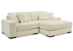 a white sectional sofa with pillows on it's back and arms, facing the corner