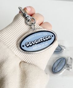 a hand holding a keychain with the word sevenzen on it and two buttons