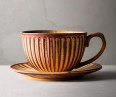 a coffee cup and saucer sitting on top of a white countertop next to a gray wall