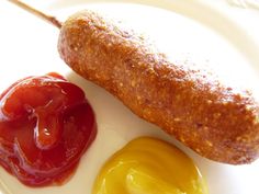 an egg, ketchup and mustard on a white plate with a pickle