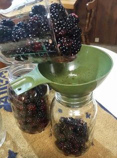 berries are being poured into jars on the table