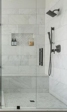 a walk in shower sitting next to a white tiled wall with black fixtures on it