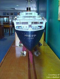 a model of a cruise ship on display in a room with blue walls and wooden floors