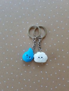 two blue and white clouds are attached to silver metal key chains on a polka dot background