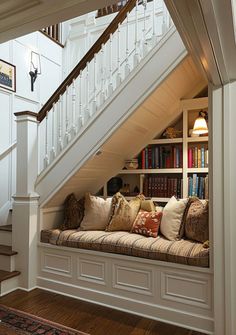 there is a window seat under the stairs in this house with bookshelves on either side