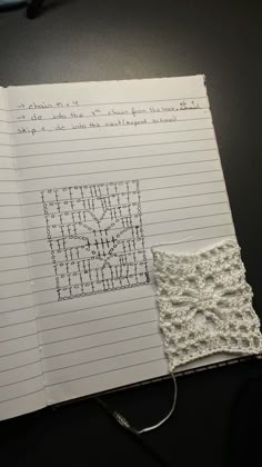 an open notebook with crochet on it and a piece of paper next to it