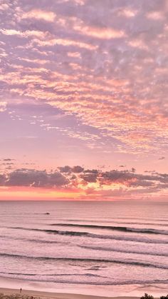 the sun is setting over the ocean and people are walking on the beach