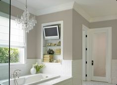 a bathroom with blue walls and white trim, including a tv mounted above the bathtub