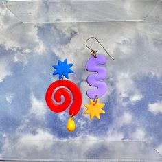 a pair of colorful earrings hanging from hooks on a cloudy background with the word sale spelled out