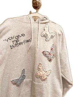 a white sweatshirt with embroidered butterflies on the back and words that say, you give me butterflies