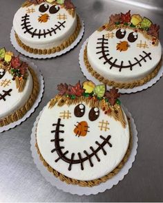 three decorated cakes sitting on top of a metal counter covered in frosting and decorations