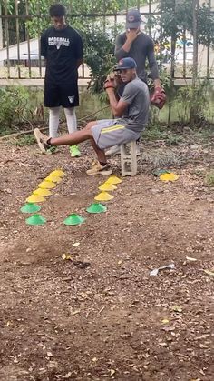 three young men are playing baseball in the yard with their feet up and one is sitting on a bench