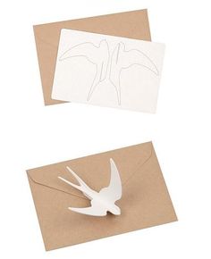 two pieces of paper cut out of the shape of a bird on top of an envelope