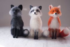 three little fox figurines sitting next to each other on top of a table