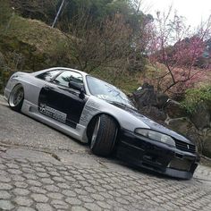 a silver car parked on the side of a road next to some rocks and trees