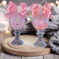 two glass vases with pink bows on them sitting on a wooden table next to other items