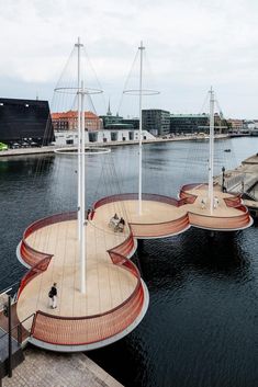 several sail boats floating on top of a body of water next to a pier and buildings