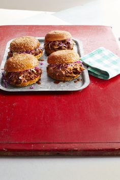 four pulled pork sandwiches on a tray