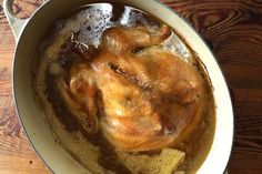 a cooked chicken in a pot on a wooden table