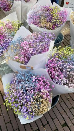 many different types of flowers in white paper bags