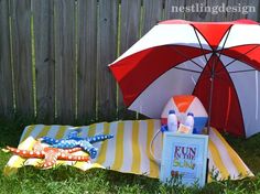 an open umbrella sitting on top of a blanket next to a book and other items