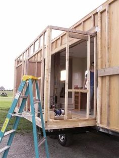 a man standing on a ladder next to a tiny house