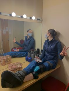 two people sitting on a table in front of a mirror