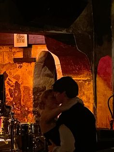 a man and woman are kissing in front of a stage with musical instruments on it