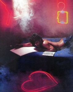 a woman laying on top of a bed in a room with neon signs above her