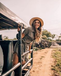 a woman wearing a hat standing on the back of a truck