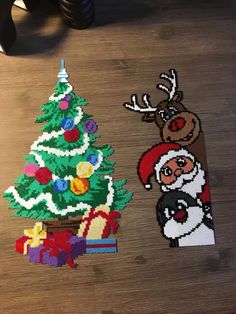 two pieces of beaded christmas decorations on a wooden table next to a small tree