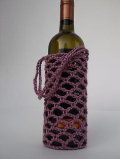 a crocheted wine bottle bag with a corkscrew handle is sitting next to a bottle of wine