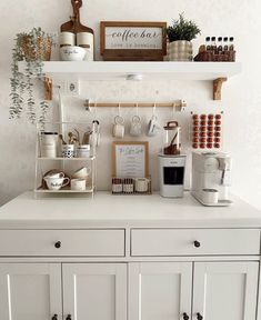 a coffee bar with white cabinets and shelves filled with cups, mugs and other items