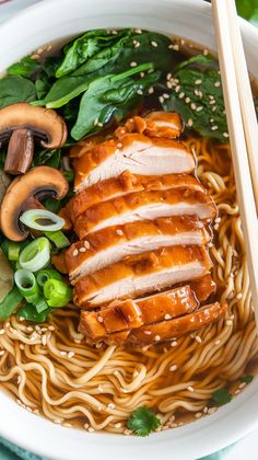 a white bowl filled with meat and noodles next to chopsticks on a table