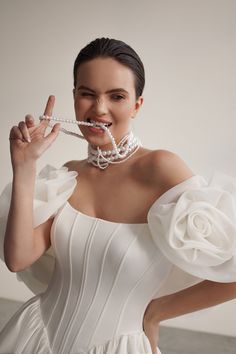 a woman in a white dress is holding something up to her mouth