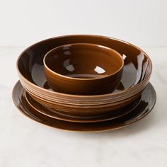 a stack of brown plates sitting on top of a white countertop next to each other