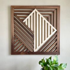 a plant is sitting on a table in front of a wooden frame with geometric designs