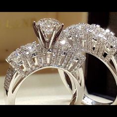 two wedding rings with diamonds on them sitting next to each other in front of a mirror