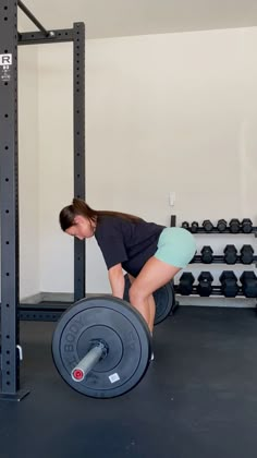 a woman squats on the ground with a barbell in front of her as she works out