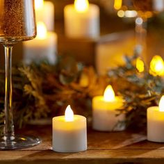 lit candles sit on a table next to a wine glass