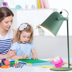 a woman and child sitting at a table with art supplies