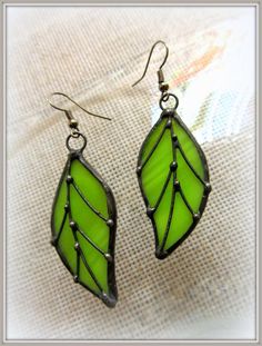 a pair of earrings with green leaves on them