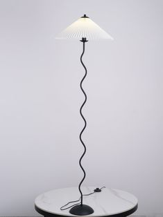 a lamp that is sitting on top of a white table with a black cord attached to it