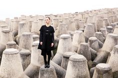 a woman standing in the middle of rows of cement vases